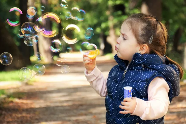 Foto av liten flicka som blåser såpbubblor.
