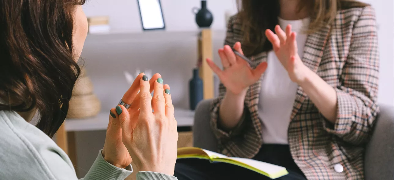 Två ljusa kvinnor i en soffa pratar med varandra.foto